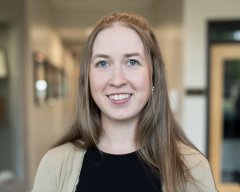 Alicia Reed, with long hair, a black top and tan sweater.